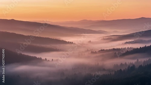 Breathtaking scenic view of misty mountain ridges during a beautiful golden sunrise.