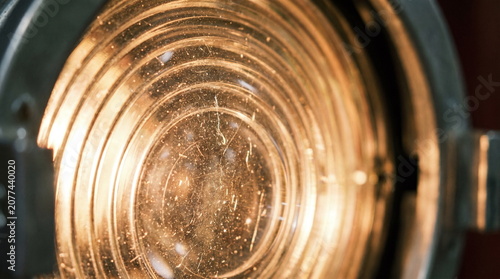 Close up of a warm illuminated dusty and scratched glass fresnel lens on a theatrical stage spotlight