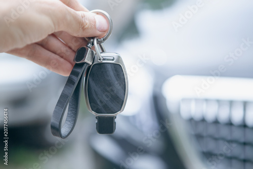 Hand holding car key on blurred background. Close up of car key.