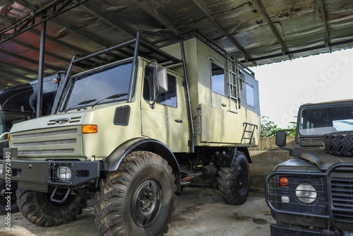 Rugged Off Road Camper Truck With Large Tires And A Tall Roll Cage Is Parked