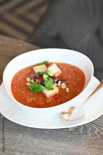 Bild auf Leinwand Gazpacho served with avocado and olives in a white bowl, top view of an elegant