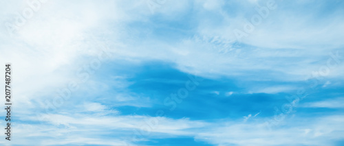 the sky is clear blue with fluffy white clouds, the sky is very bright, and the sun shines.