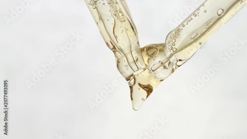 Yellow gel dripping from pipettes on neutral background, front view.