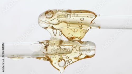 Several pipettes arranged horizontally with yellow cosmetic serum, peptide on a neutral background.