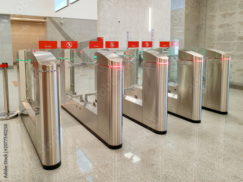 Canvastavla row of modern stainless steel turnstiles with glass barriers and red no exit signs