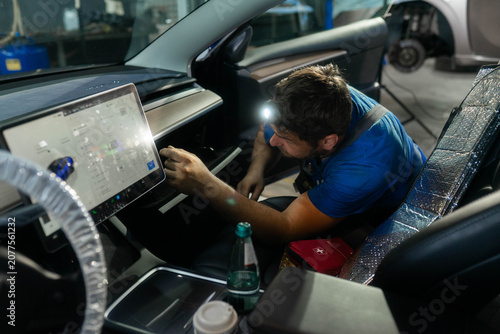 фотографія Car cabin shows large touchscreen and open glove box in workshop