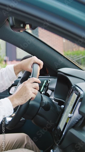 Handsome smiling man sitting inside a modern car, setting a navigation route while looking at the camera. Concept of travel planning, navigation technology, road trip, transportation, mobility, GPS