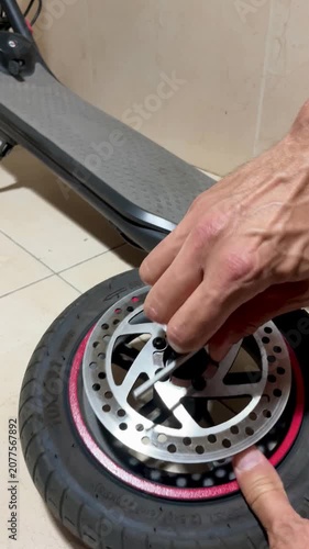 Hand removing brake disc from electric scooter wheel to fix a punctured, worn or damaged tire