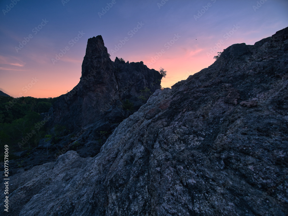 Obraz premium Limestone mountains at dawn, featuring a sharp and unique landscape with sparse vegetation set against a backdrop of sky and clouds in Surat Thani Province, Thailand.