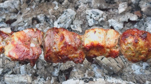 Pork pieces in mustard marinade roast on a skewer over smoldering coals