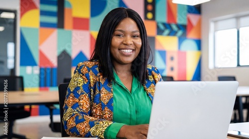 young African woman working on laptop in a modern colorful office/ coworking space