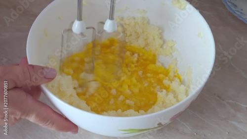 Mixer beaters blend yolks with creamed butter and sugar in a deep bowl