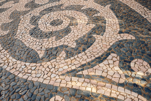 Pattern of stones on  sidewalk in  city. daylight hours showing artistic design. sidewalk features a design made of various stones arranged in curves and swirls. artwork  pavement patterns during day