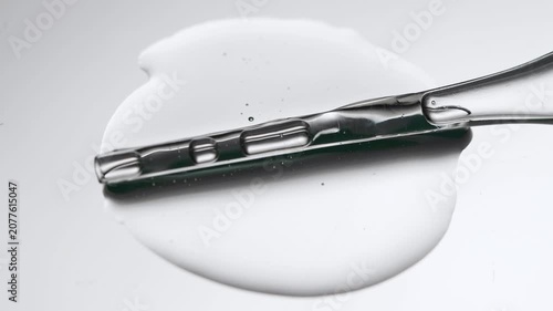 Medical pipette with transparent solution, liquid serum close-up on gray background.