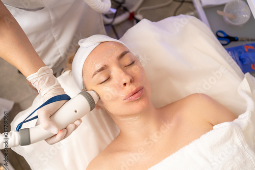 Woman undergoing a professional facial skin treatment with a beauty machine in a clinic