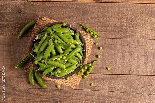 Fresh green peas and pods in a bowl on wooden table. Vegetable healthy food.  