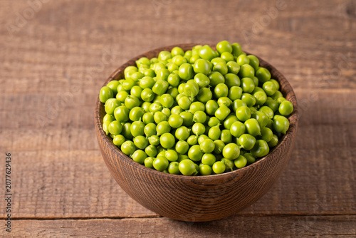 Fresh green peas and pods in a bowl on wooden table. Vegetable healthy food.  