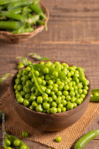 Fresh green peas and pods in a bowl on wooden table. Vegetable healthy food.  