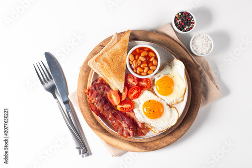 Delicious traditional English breakfast with fried eggs, beans, bacon, tomatoes and toasts