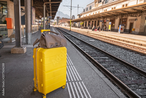 Yellow suitcase on railway platform ready for travel journey