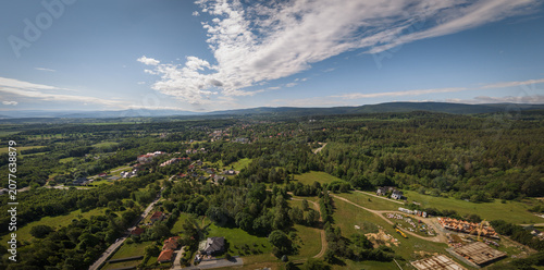 Panoramic aerial photograph of Polanica-Zdrój with the Sudety Mountains in the background, showing a late spring mountain landscape