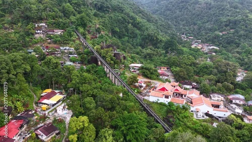 Drone footage shows Penang Hill funicular railway running through forested hillside near temple and village.