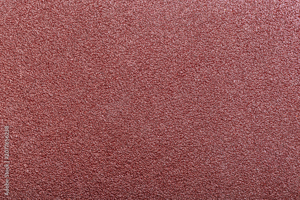 Fototapeta premium Red abrasive sandpaper belt texture with dense grit and rough uneven surface detail