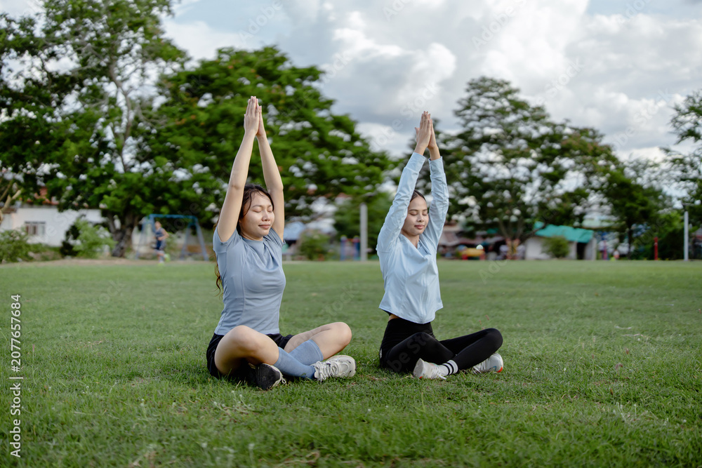 Fototapeta premium Young Women Practicing Seated Yoga with Raised Hands During Outdoor Mindfulness Session