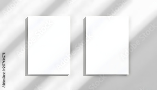 Two empty white vertical rectangle poster or business card mockups with diagonal dappled light spots on gray concrete wall. Flat lay, top view. For advertising, brand design, stationery presentation