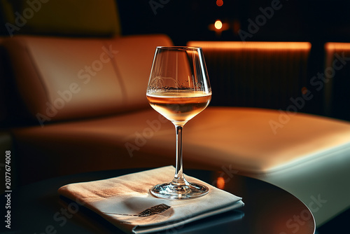 Elegant glass of white wine on table with sofa