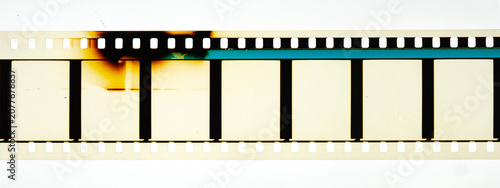 Long horizontal vintage 35mm motion picture film strip featuring blank frames and classic sprocket holes. Authentic analog cinema celluloid isolated on white with dark burn marks and light leaks