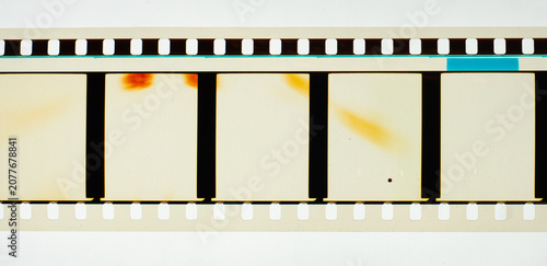 Long horizontal vintage 35mm motion picture film strip featuring blank frames and classic sprocket holes. Authentic analog cinema celluloid isolated on white with subtle orange light leaks