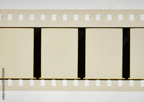 Vintage 35mm motion picture film strip featuring blank empty frames and classic sprocket holes. Authentic analog cinema celluloid isolated on a bright white background for retro template design