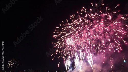 Vibrant pink and white fireworks display exploding in night sky for celebration, new year eve, and independence day festive background