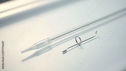 Slender balloon catheter and miniature stent on surgical tray, metallic shine.