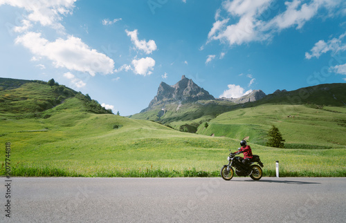 Motorcyclist riding on alpine mounain road in the Alps in summer