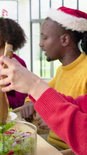 Vertical video: Serving holiday meal at long table, friends in festive sweaters passing salad bowl