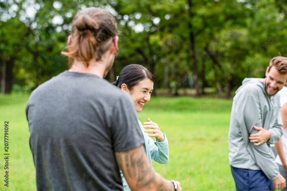 Fototapeta premium Smiling Asian woman laughing with men during outdoor group activity