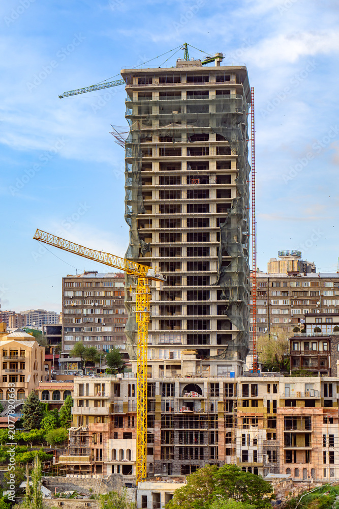 Fototapeta premium High-rise building in progress, cranes active, cityscape background, clear sky
