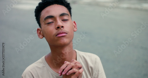 Obraz na plátně Teenage boy with a peaceful expression, eyes closed, hands clasped in a prayerfu