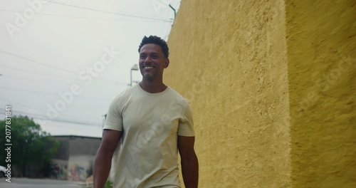 Tableau sur toile Hispanic Afro-Latin man walking forward along yellow wall, confident and relaxed
