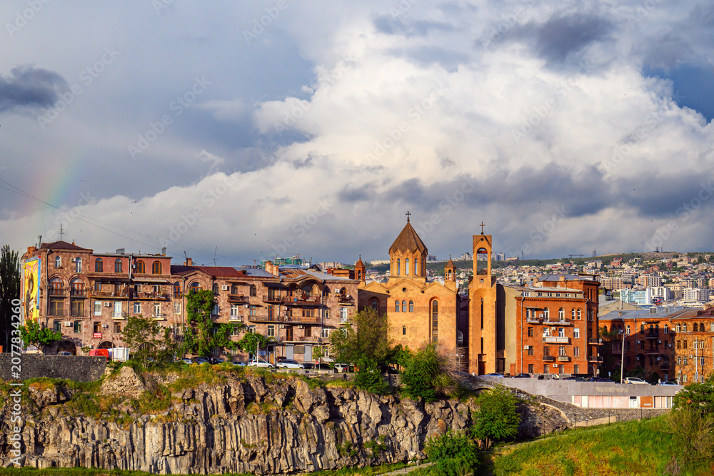 Obraz premium City skyline with church towers and terracotta roofs under rainbow