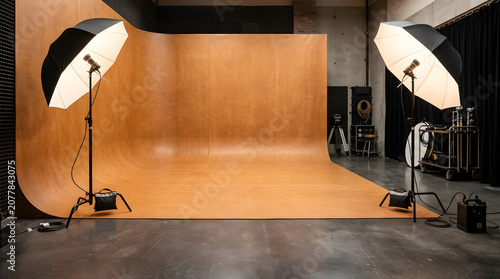 Photographers set up softbox lights on stands in a studio with a wooden backdrop.
