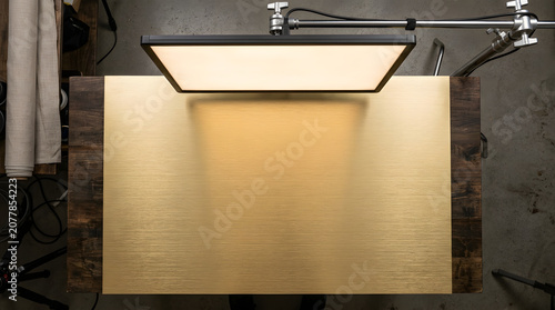 A studio light shines on a gold background in a photography setup indoors.