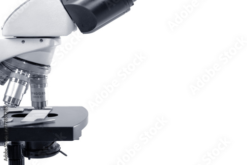 Close-up of laboratory microscope with glass slide on white background, scientific research concept with copy space.