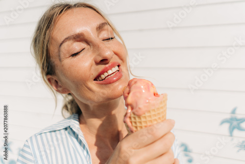 Foto Woman enjoying melting ice cream cone on a sunny summer day, smiling with eyes c