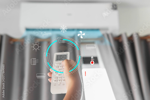 Fotografie A hand holding an air conditioner remote, setting the air conditioner to the app
