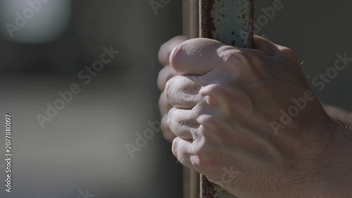 Close up of a person's hand gripping rusty metal bars, illustrating concepts of struggle, confinement, and hope.