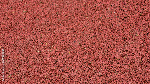 Foto A top-down view shows the uniform, rough-textured surface of a reddish-brown rubberized running track or playground flooring
