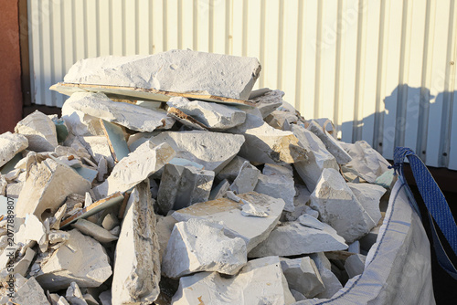 Construction demolition waste pile near industrial building. Broken insulation boards and rubble create textured background. Building renovation generates heavy debris. Recycling and disposal concept.